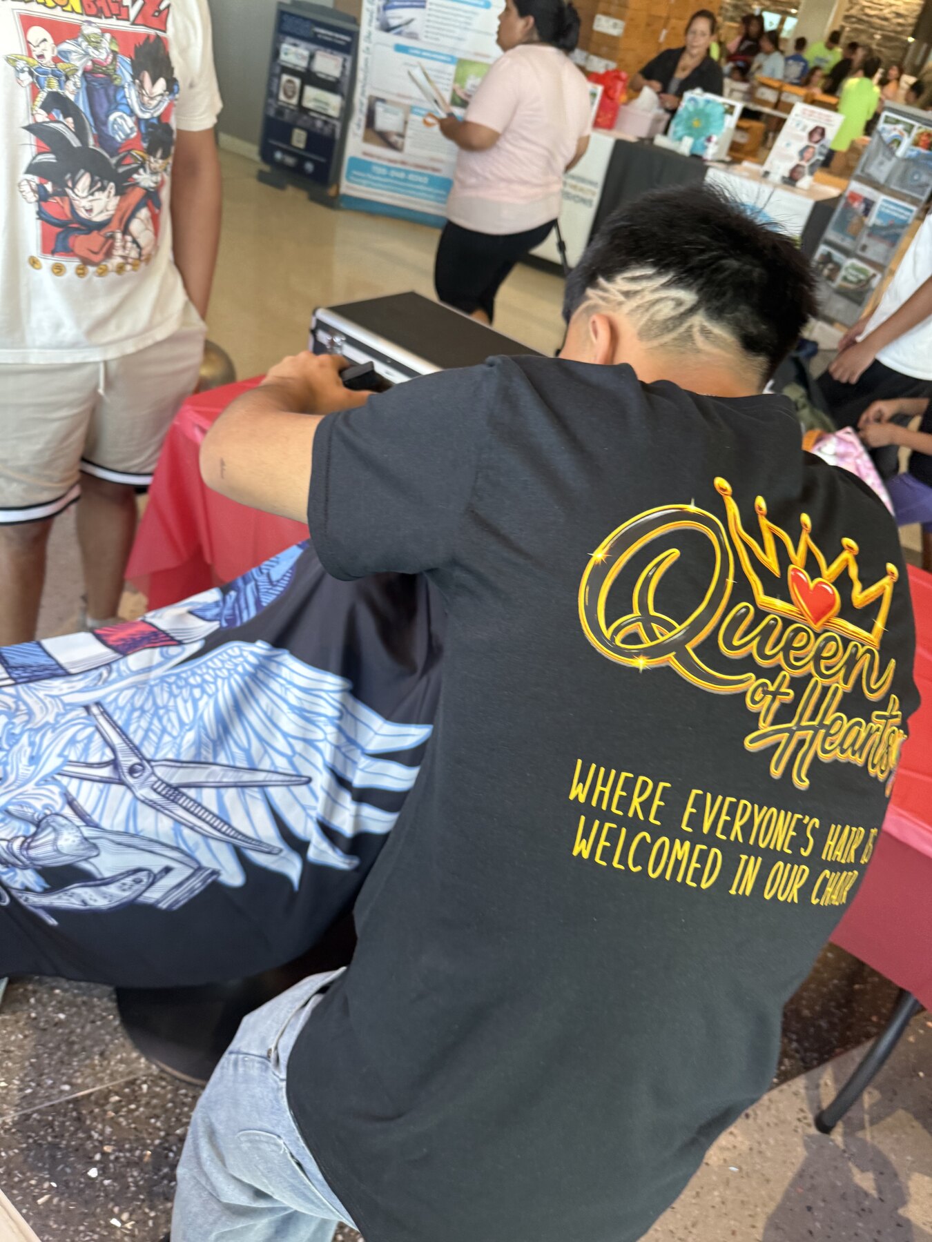 Queen of Hearts volunteer creating a detailed haircut design at the giveback
