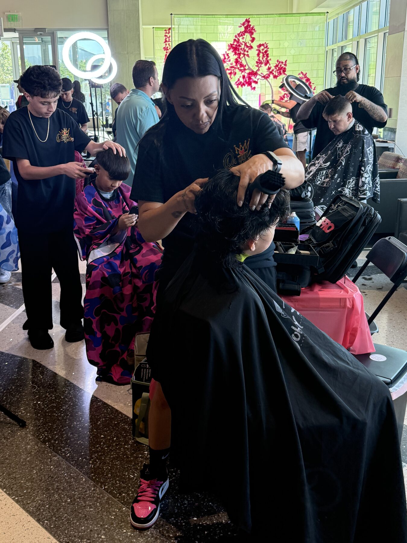 Queen of Hearts volunteers cutting children's hair at the giveback